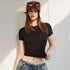 Person wearing a black crop top and blue jeans with a red cap indoors.